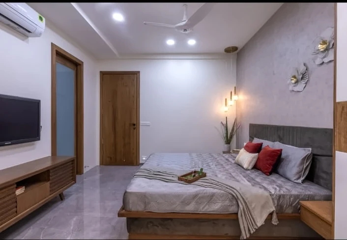 Bedroom with grey upholstered bed and integrated media unit